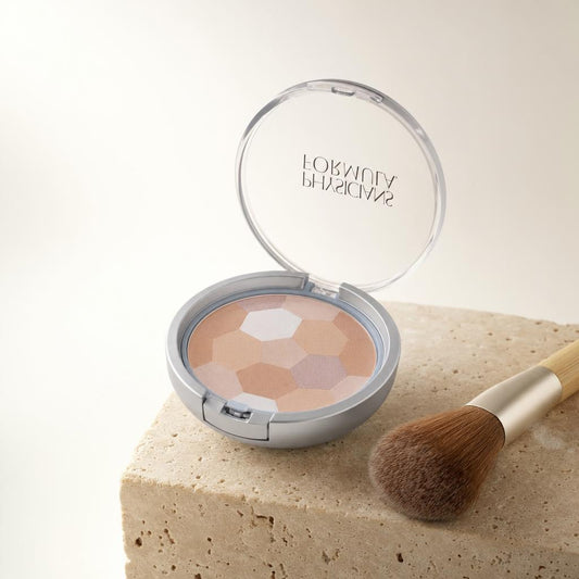 Polvos compactos multicolor Physicians Formula abiertos sobre travertino con brocha