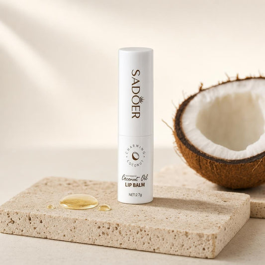 Bálsamo labial de aceite de coco SADOER sobre piedra de travertino junto a un coco